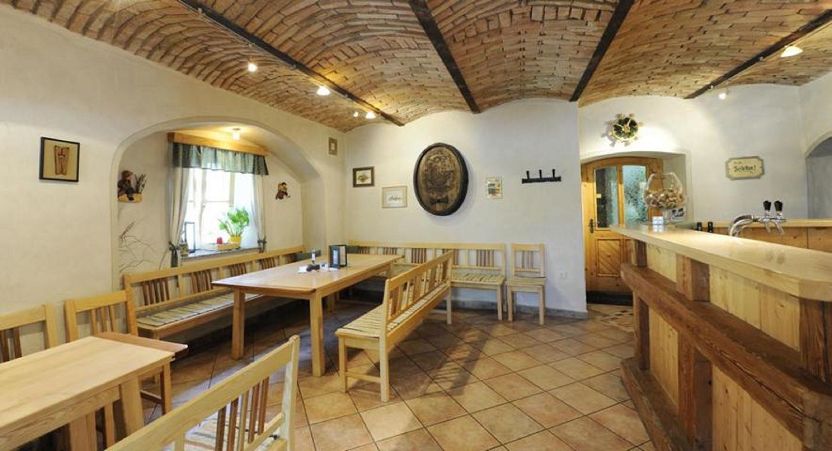Interior view of a traditional wine tavern with wooden furniture and brick vaults.