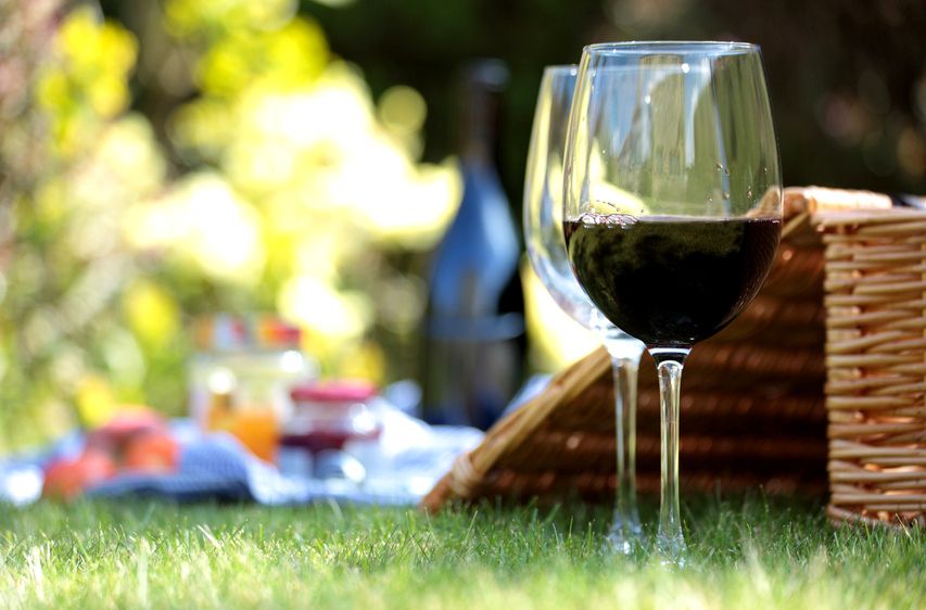 Two wine glasses and a picnic basket on a meadow.