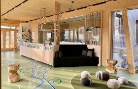 Interior view of a modern foyer with wooden elements, a bench and decorative stones on the floor.