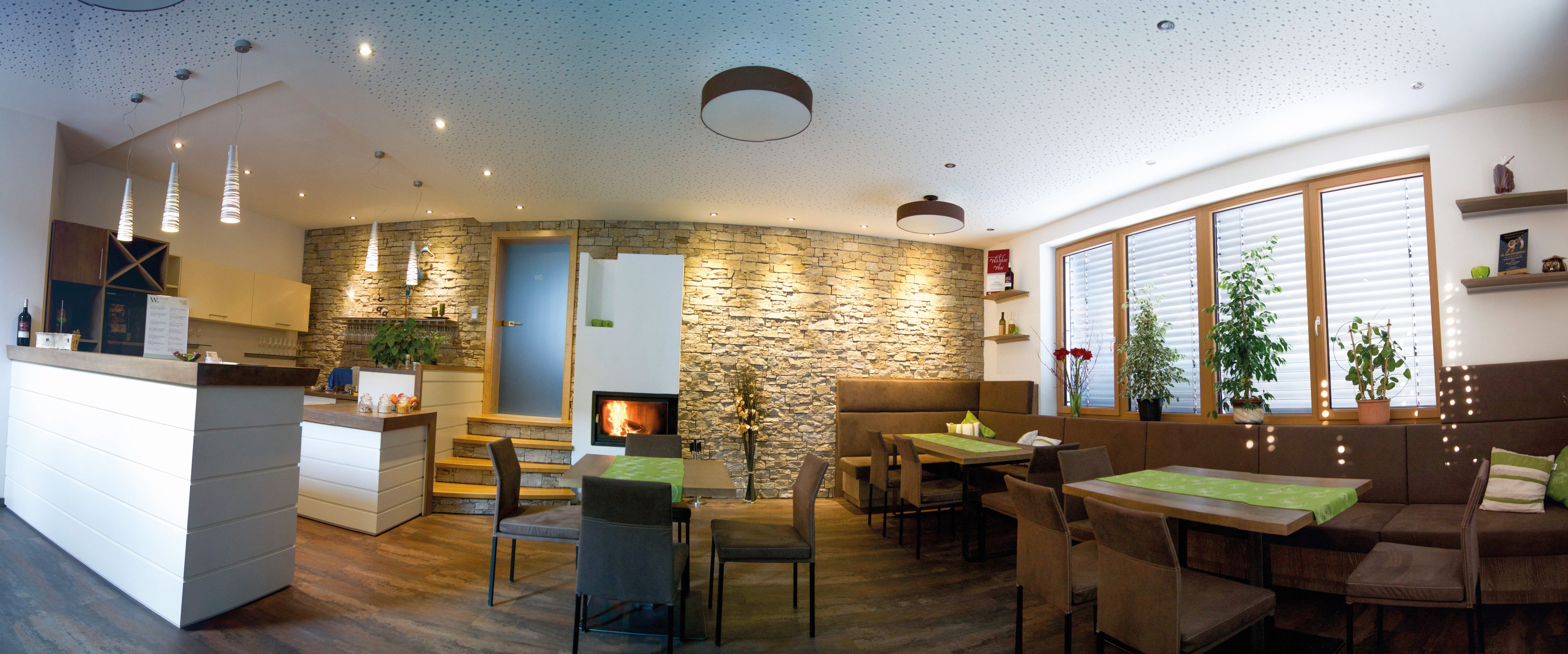 A modern tasting room with wooden furniture, stone wall, fireplace and plants.