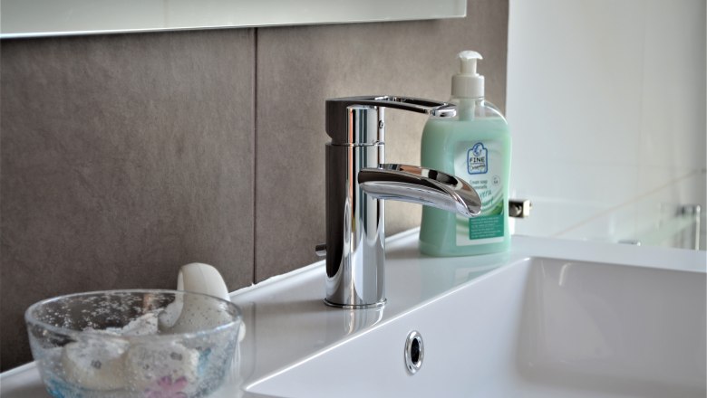 Close-up of a washbasin with soap dispenser and glass with soap.
