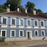 Blue historic building with white window frames and tiled roof.