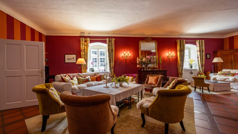 Elegant living room with red walls, comfortable armchairs and a large mirror.