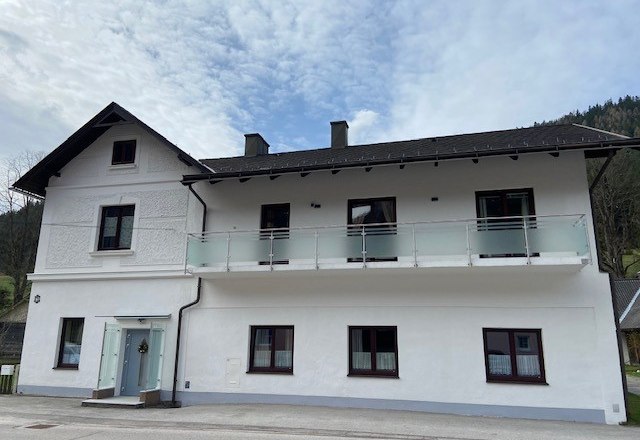 Private room Strasser, © Wiener Alpen Two-story white house with balcony and blue sky in the background.