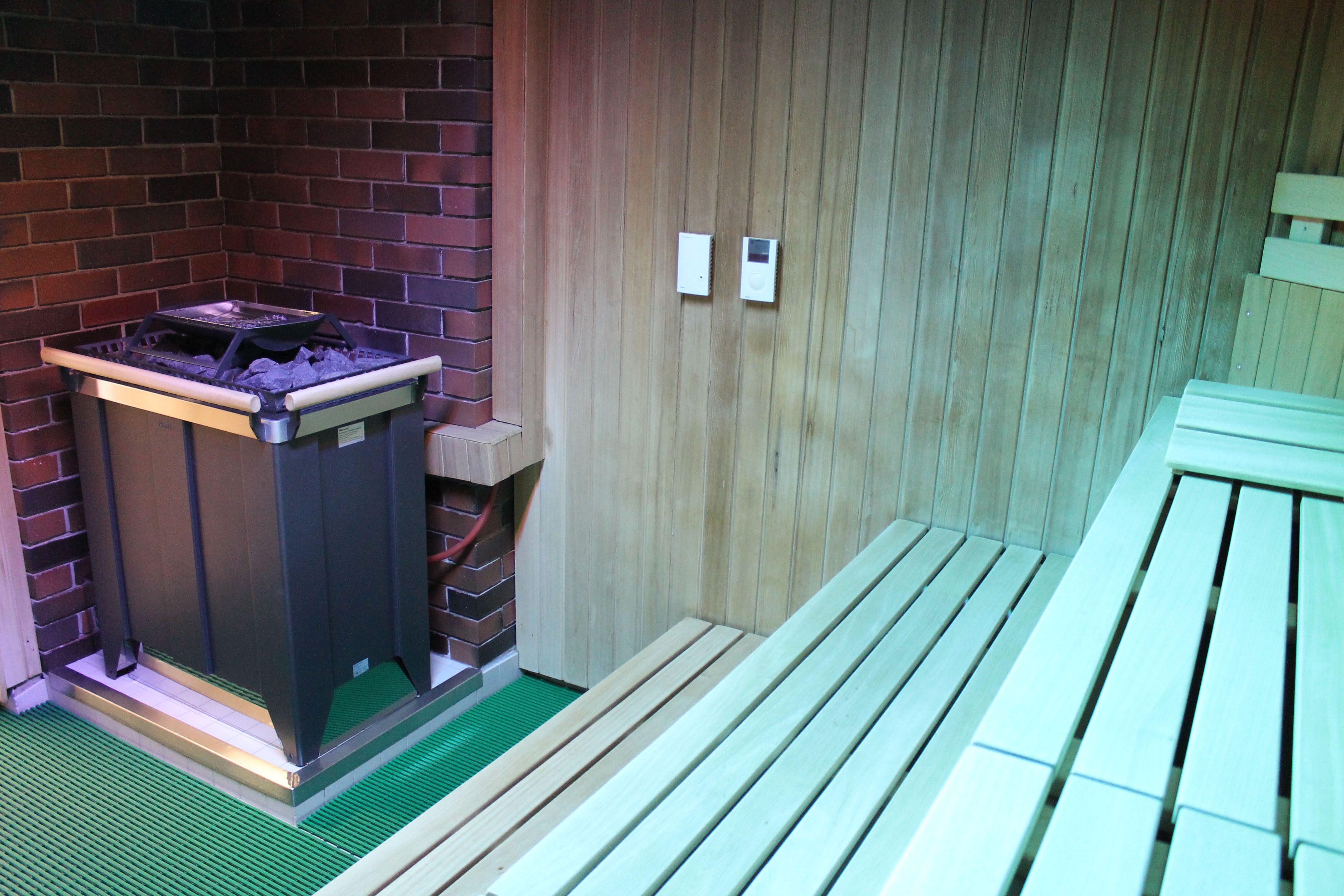 Interior view of a sauna with wood paneling and sauna heater.