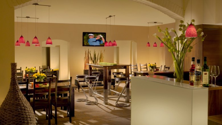 Interior view of a stylish restaurant with modern furniture and red hanging lamps.