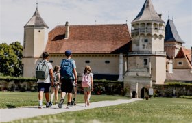 Children with rucksacks walk towards a castle.