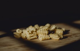 Close-up of uncooked, spiral-shaped noodles on a wooden base.