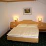 A simply furnished hotel room with a double bed, two bedside lamps and pictures on the wall.