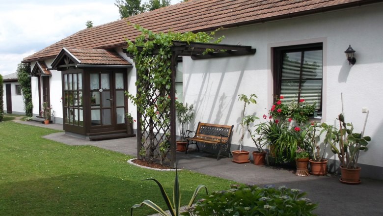 Guesthouse Schlossblick, © Marschik Well-kept garden with many potted plants and the entrance doors to the apartments.