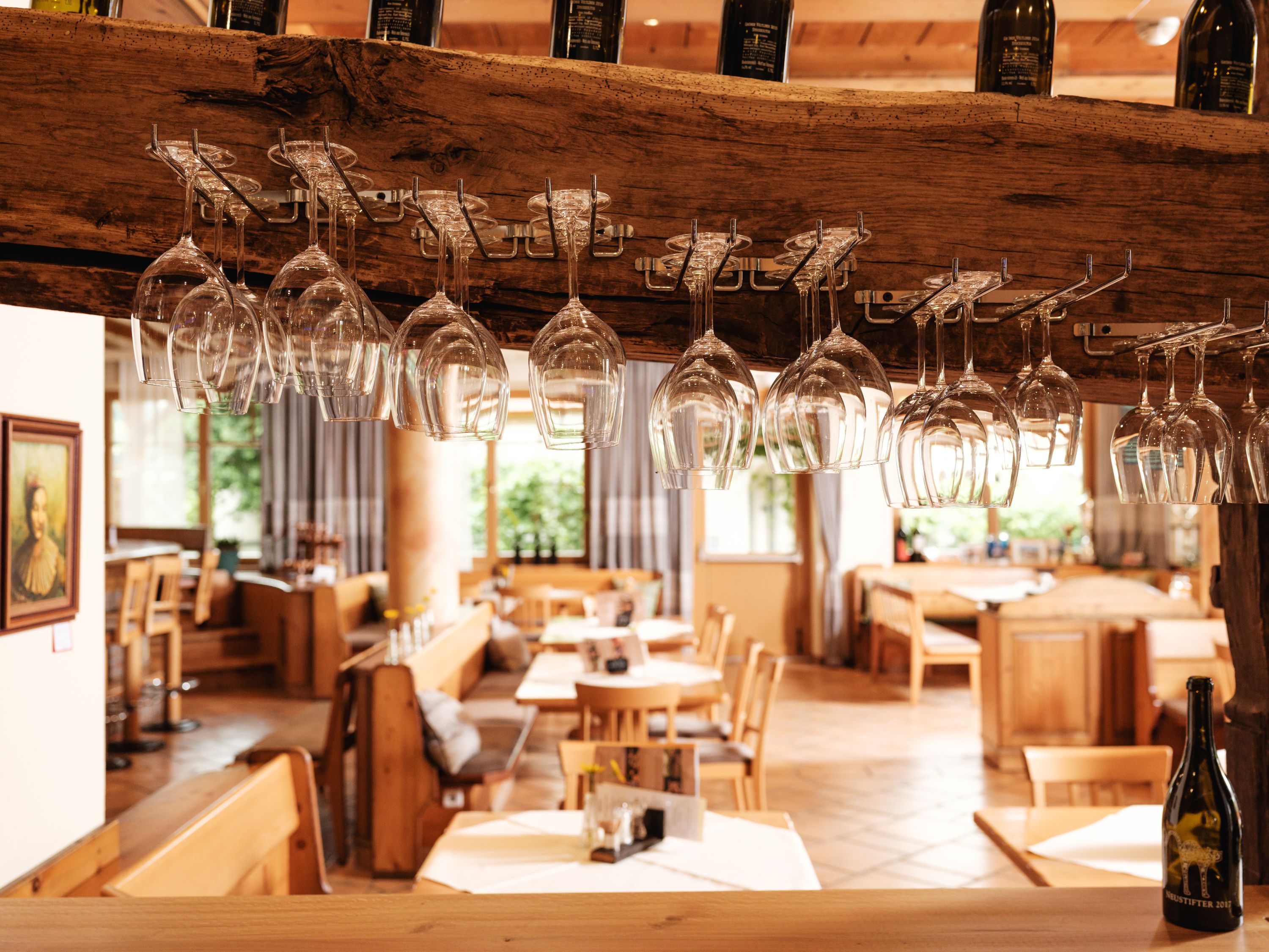 Interior view of a restaurant with hanging wine glasses and wooden furniture.