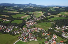 Aerial view of Z&ouml;bern, a rural community with houses and fields, surrounded by hills and forests.