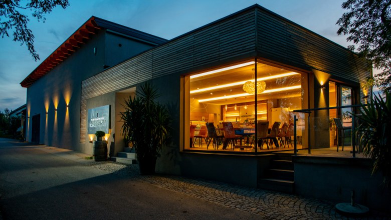 Modern building with glass front and interior lighting at dusk.