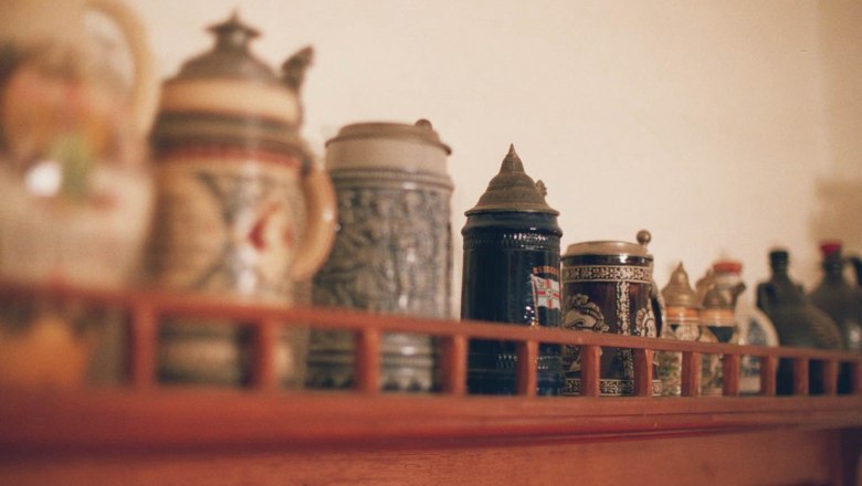 A collection of beer mugs on a wooden shelf, blurred in the foreground.
