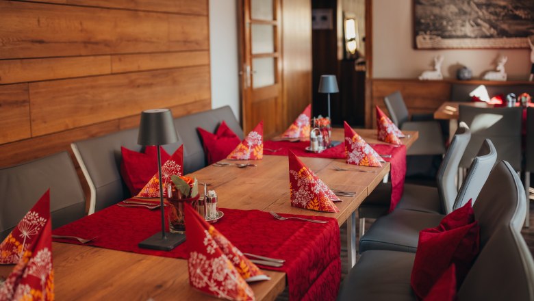 Comfortably laid table in a restaurant with red napkins and table runners.