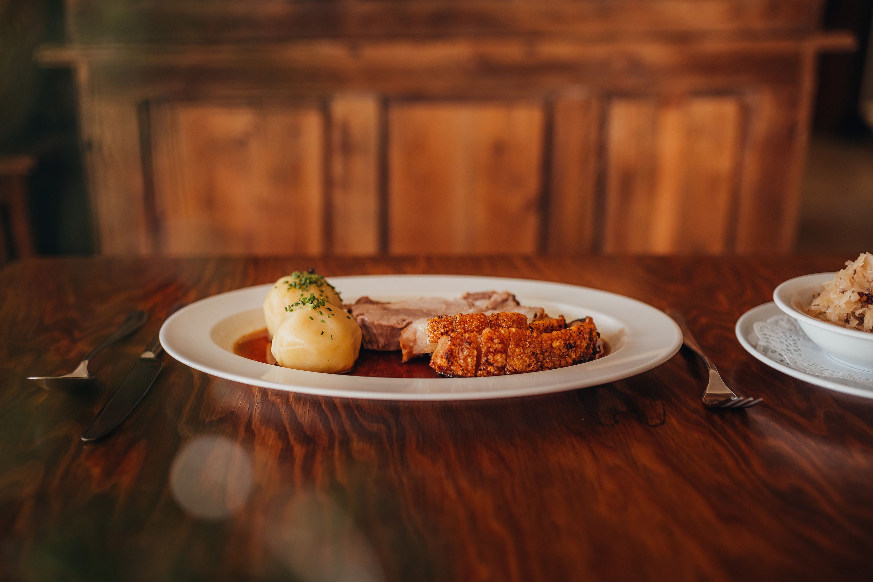 Traditional dish with roast pork and dumplings on a wooden table.