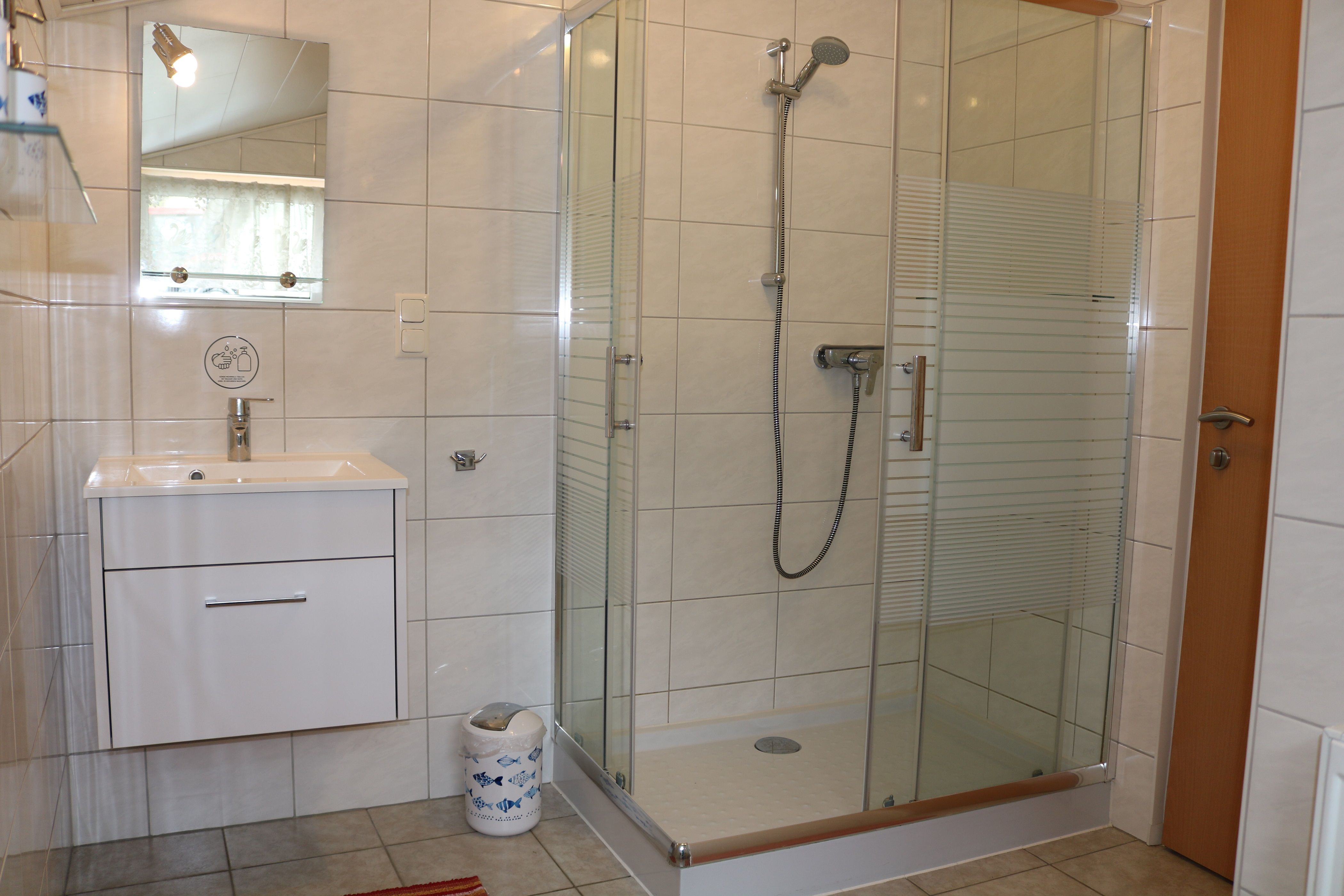 Modern bathroom with shower, washbasin and mirror.