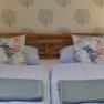 Comfortable double bed with wooden headboard, blankets and pillows and bedside tables with lamps.