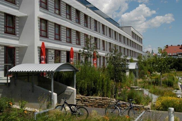 Kolping Campus Krems GmbH, © Kolping Campus Krems GmbH Modern building with several floors, surrounded by green landscape and bicycles in the foreground.