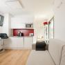 Modern apartment with kitchenette, sofa and bar stool.