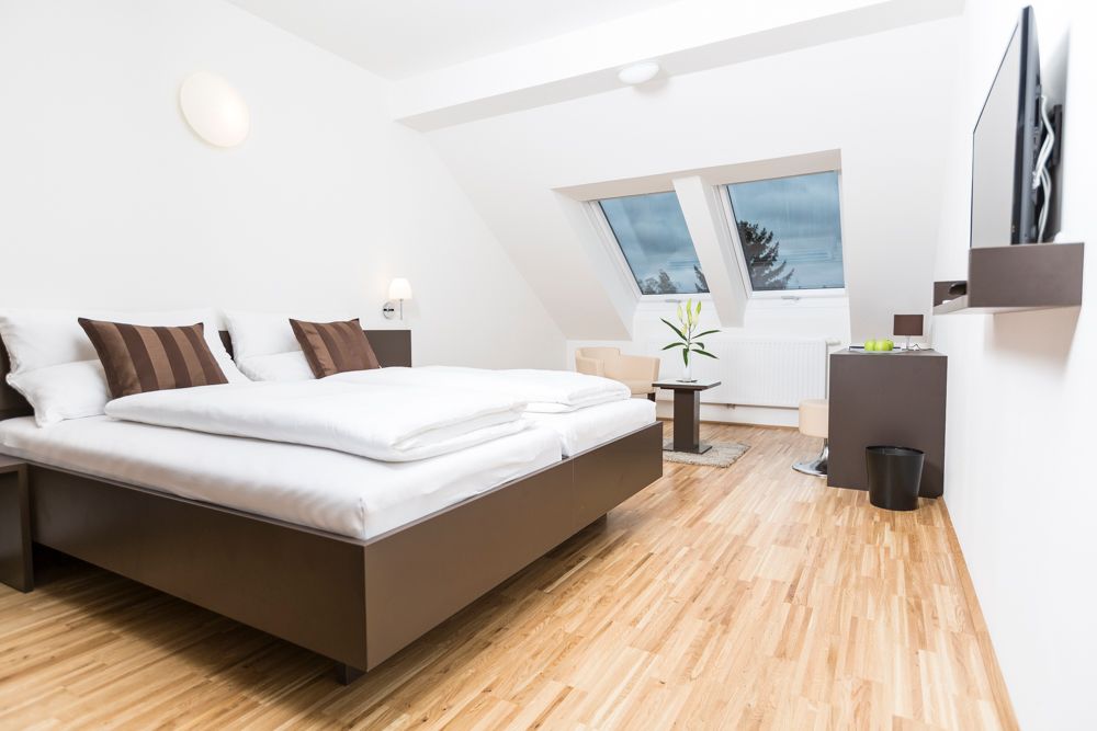 Modern guest room with double bed, skylights and wooden floor.