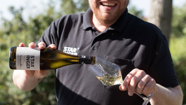 Man pouring wine into a glass outdoors.