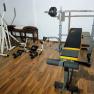 A fitness room with weight bench, cross trainer and dumbbells on a wooden floor.
