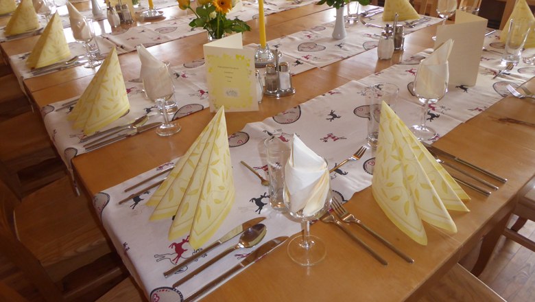 Festively laid table in an Alpine inn with yellow napkins and flowers.