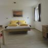 Modern guest room with double bed, wooden furniture and yellow cushions.