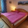 Cozy double room with wooden bed, pink bed linen and bedside tables with lamps.