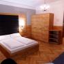 Modern apartment with wooden furniture, double bed, wardrobe, chandelier and kitchenette.