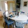 Dining area in a kitchen with round table, blue chairs and breakfast table.