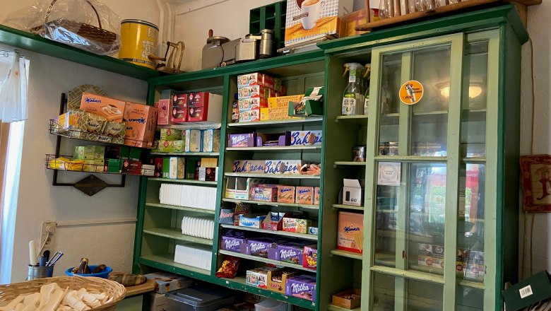 A traditional store with green shelves filled with various groceries and household goods.