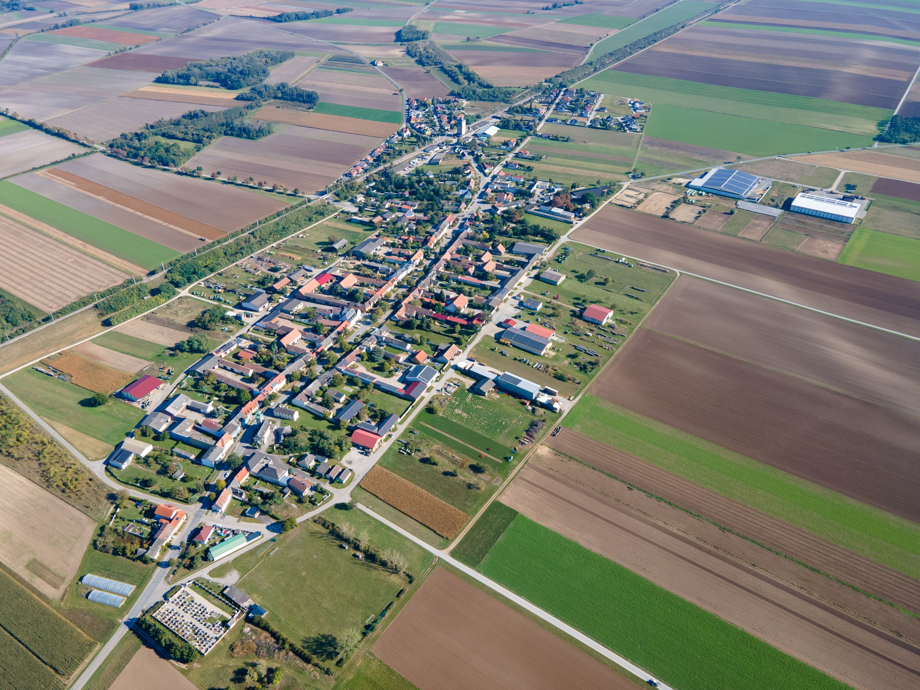 Aerial view of the town of Weiden an der March, with a densely built-up town center surrounded by fields and farmland.