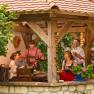 A group of people sit in a covered, rustic pavilion and enjoy wine and company.