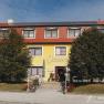 Yellow building with a red roof and the inscription 'Scheiterer', surrounded by trees and bicycles.