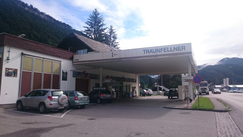 A gas station with the name Traunfellner in a rural setting with mountains in the background.