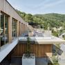 Modern spa terrace with wood paneling and views of wooded hills.