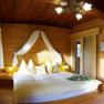 Cozy bedroom with wooden walls and double bed.