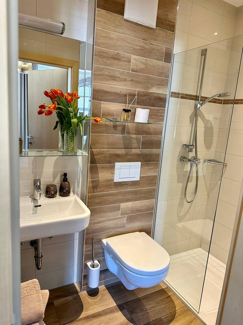 Modern bathroom with shower, washbasin, toilet and flowers.