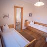 Two single beds in a cozy room with wooden furniture and pictures on the walls.