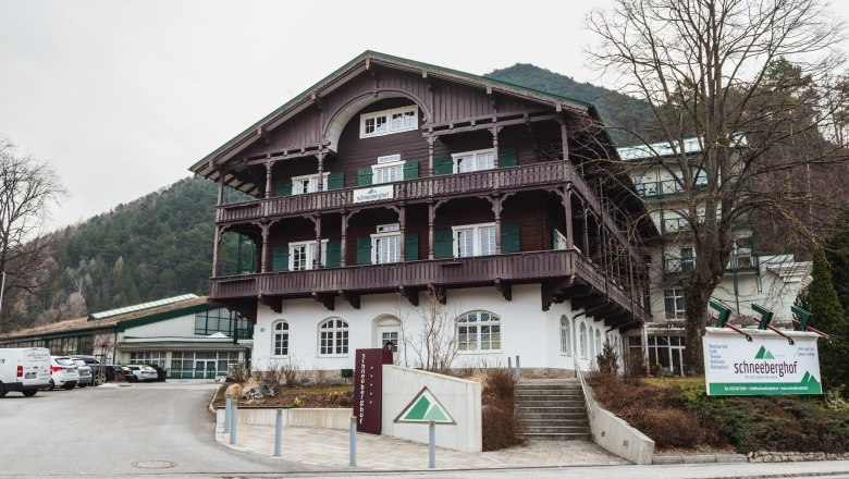 Hotel Schneeberghof in a mountainous setting with traditional architecture and a large sign in front of the building.