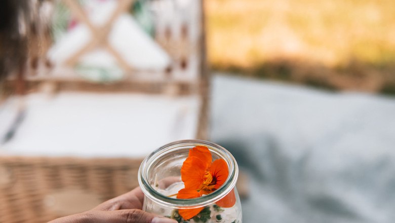 Close-up of a dessert glass with an orange flower, a picnic basket in the background.