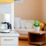 Coffee machine on kitchen counter with living room in the background.