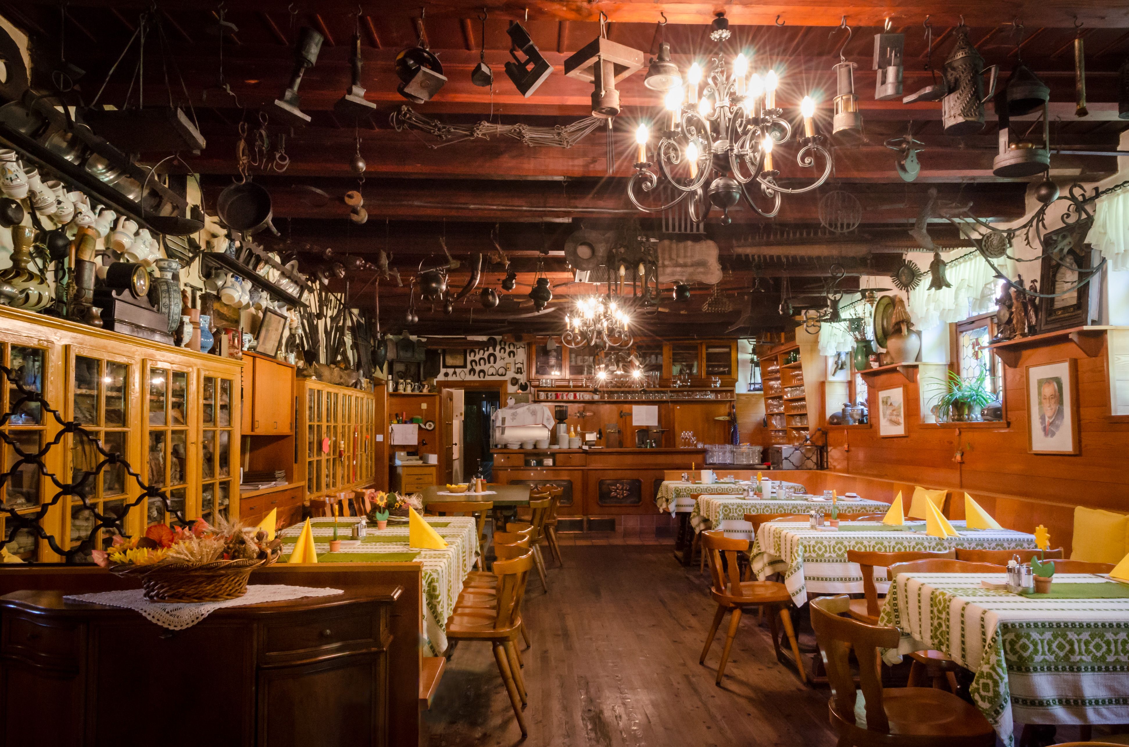 Interior view of a traditional inn with wooden furniture and decorative objects on the ceiling.