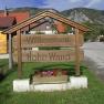 Wooden sign with the inscription 'Welcome to the municipality of Hohe Wand' in front of a mountain landscape.