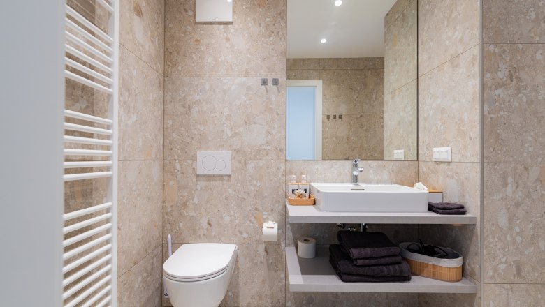 Modern bathroom with washbasin, mirror, toilet and towel rail.