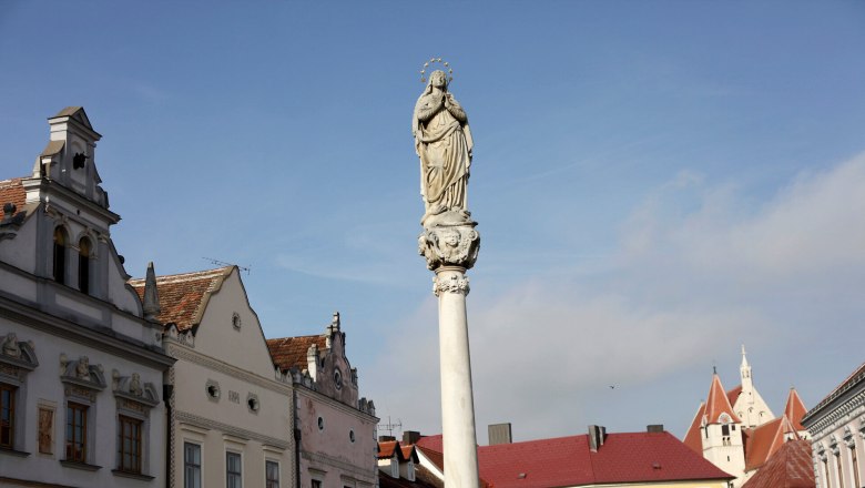 Statue on a pillar in Eggenburg with historical buildings in the background.