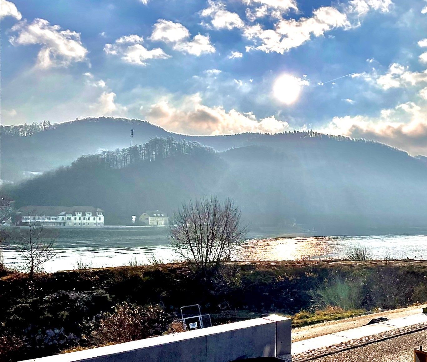 Sunbeams over a river with hills in the background.