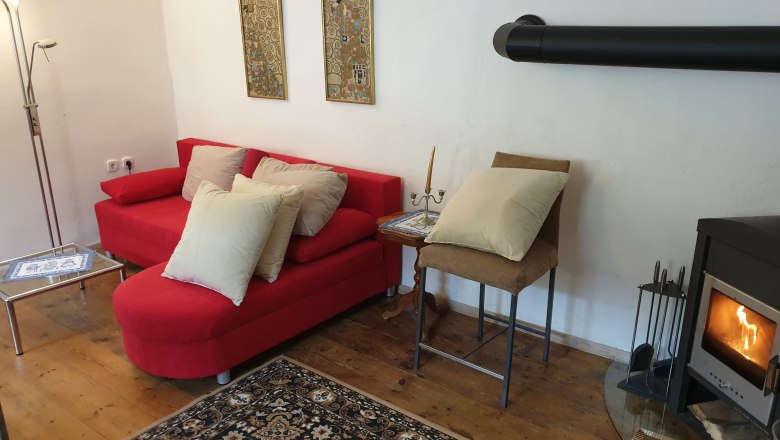 Cozy living room corner with red sofa, fireplace and carpet.